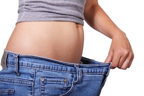 Woman showing weight loss by wearing too large jeans