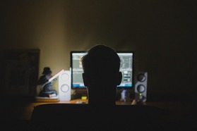 Silhouette of a man sitting in front of a computer screen